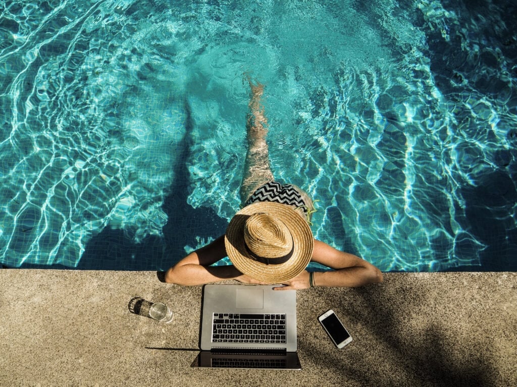 Young woman with laptop at swimming pool for the article 22 Real Online Businesses You Can Start From Anywhere